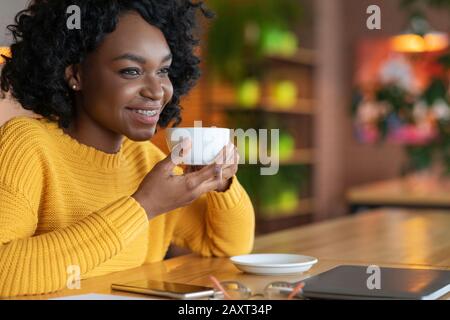 Nahaufnahme des träumerischen schwarzen Mädchens, das eine Tasse Kaffee genießt Stockfoto