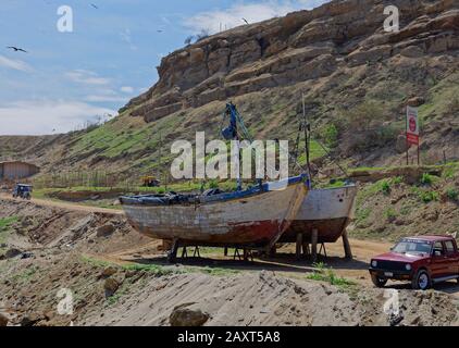 Zwei peruanische Fischerboote aus Holz rappten an Land und warteten auf einige Wartungsarbeiten unter den Sandsteinfelsen von Mancora. Stockfoto