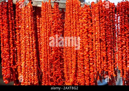 Farbenfroher Korallenschmuck. Halsketten Auf einem Stall auf dem Wochenmarkt, Sommermarkt, Baia Sardinien, Gallura, Sardinien, Italien. Stockfoto