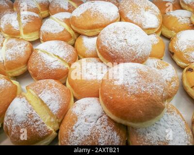 Frische Donuts gefüllt mit Sahne und ohne in einer Bäckerei auf dem Regal zum Verkauf bereit Stockfoto