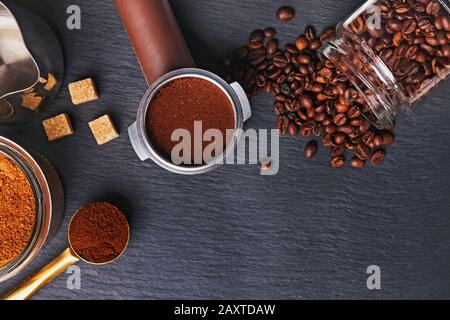 Kaffeefilterhalter mit und gerösteten Bohnen, die auf schwarzem Hintergrund verteilt sind Stockfoto