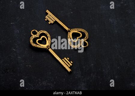 Entsperren Sie My Heart - Zwei Herzförmige Golden Vintage Keys auf schwarzem Hintergrund Stockfoto