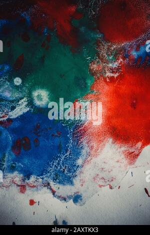 Tropfen mit Streifen unterschiedlicher Farbfarbe werden gemischt und absorbiert. Abstrakte Farbflecken auf weißem Papier Stockfoto