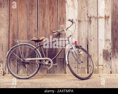 Radfahrer Outdoor-Lifestyle. Klassisches Retro-Retro-Fahrrad gegen die alte Rispenwand aus Holz zu Hause in der Landschaft Asiens. Old Bike Vintage Style Backgr Stockfoto