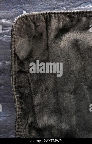 Schwarzer struktureller Hintergrund - altes schäbiges Veloursleder, Rückseite, altes Gewebe, Textil. Stück Ledertasche, Rückseite an dunklen, Sichtbaren Kanten mit Stockfoto