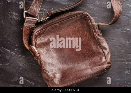 Braun stilvolles Leder alte Schultertasche mit Schultergurt auf dunklem Strukturhintergrund mit Textur. Gutes Konzept und guter Hintergrund für das Layout. Stockfoto