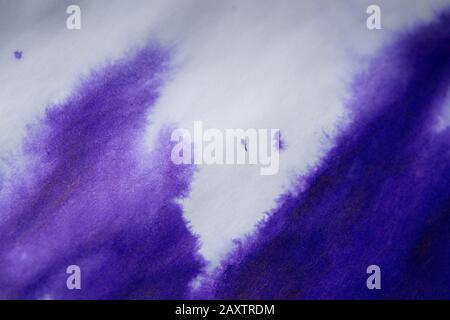 Violetter Farbfleck auf einem Blatt weißem Papiermakro. Abstrakter Hintergrund. Verteilt Tintenflecken mit Streifen auf weißem Hintergrund Stockfoto