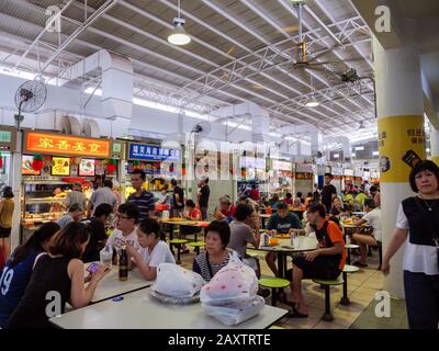 Singapur - 4. JANUAR 2020 - chinesische Diners in Asien, die in einem überfüllten Self-Service-Hawker-Center in Ang Mo Kio, Singapur, Southeas speisen und gesellig sind Stockfoto