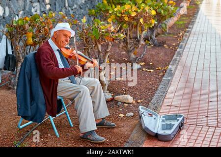 Spanien, Tenera, Adeje - 17. Dezember 2018: Der Straßenmusiker des alten Mannes spielt die Geige. Stockfoto