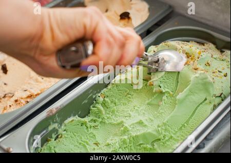 Frau wählt einen Eisball. Pistachio-Eis mit Schaufel. Stockfoto