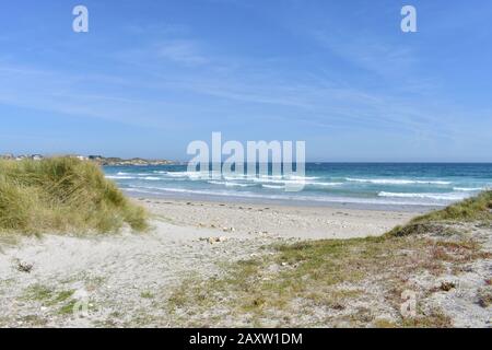 Strand mit brechenden Wellen, Felsen und Gras auf Sanddünen. Viveiro, Lugo, Galicien, Spanien. Stockfoto