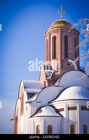 Christliche Kirche aus Ziegelpflappen und goldenen Kuppeln und Kreuze an einem sonnigen Wintertag mit blauem Himmel Stockfoto