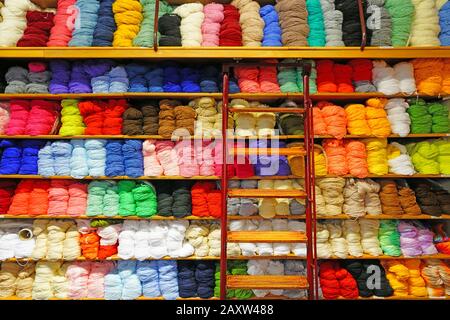 Regale mit bunten Wollgarnspulen in einem Strickladen Stockfoto