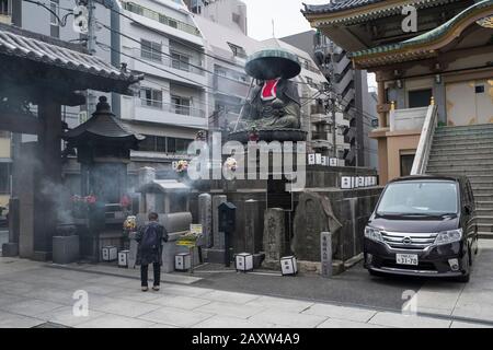 Japan, Tokio: Shinshoji-Tempel im Bezirk Sugamo. Mann vor dem Tempel und Statue von Ksitigarbha, einem Bodhisattva. Sugamo-Viertel, A. Stockfoto