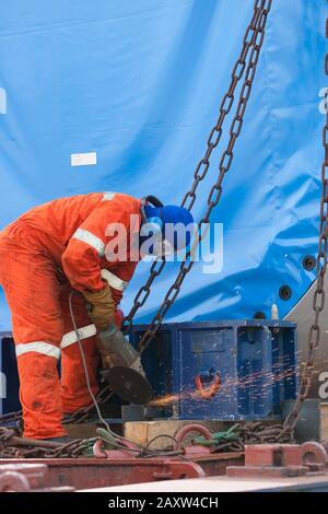 Arbeiter, der Siemens-Windenergieanlagen für den Transport an Deck sichert Stockfoto