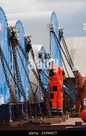 Arbeiter, der Siemens-Windenergieanlagen für den Transport an Deck sichert Stockfoto