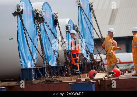 Arbeiter, der Siemens-Windenergieanlagen für den Transport an Deck sichert Stockfoto