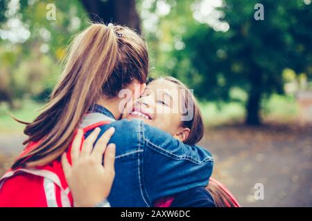 Zwei Schulfreunde umarmen, emotionales Treffen im Park. Das Konzept von Schule, Studium, Bildung, Freundschaft, Kindheit Stockfoto