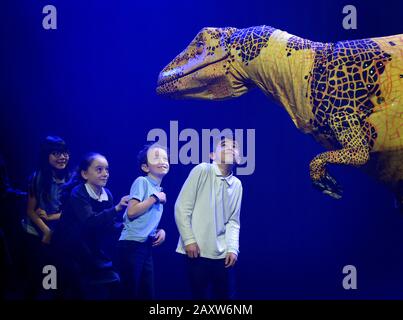 Kinder der Stockwell Primary School in London interagieren mit einer Fukuiraptor Dinosaurier-Marionette aus Erths Dinosaurier-Zoo in der Queen Elizabeth Hall im Southbank Center, London, vor einer Aufführung im Rahmen des Imagine Children's Festivals. Stockfoto