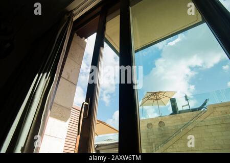 Morgensommerlicht durch das offene Fenster und Sonnenschirm im Hintergrund, niedriger Winkel Stockfoto
