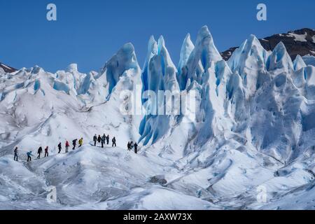 Touristen, die auf dem Perito Moreno Gletscher im Los Glaciares Nationalpark in der Nähe von El Calafate in Argentinien, Patagonien, Südamerika wandern. Stockfoto