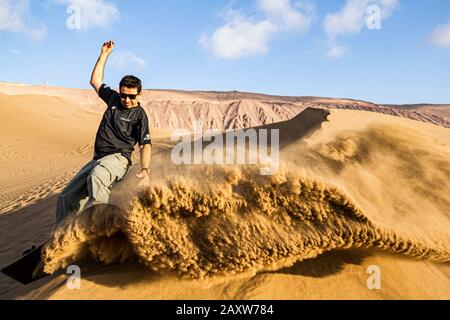 Sandboarding in Cerro Dragon, in der Atacama-Wüste. Iquique, Tarapaca Region, Chile. Stockfoto