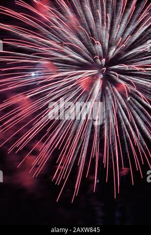 Das explodierende Feuerwerk-Display erzeugt einen bunten Kontrast von Farbe und verschwommener Bewegung gegen einen verdunkelten Nachthimmel. Spektakulärer Anblick in Baltimore MD. Stockfoto