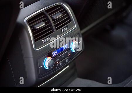 Bedienfeld mit digitalem Mehrfarbendisplay und Knöpfen für den Rücksitzpassagier in modernem Prestige Luxusauto-Interieur selektive Fokussierung mit Kopierspac Stockfoto