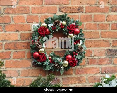 Ein Weihnachtskranz mit Blumenmuster, Der an einer Ziegelwand Hängt. Stockfoto