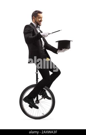 Zauberer führt einen Zaubertrick mit Zauberstab und Hut durch und reitet ein Einrad, das auf weißem Hintergrund isoliert ist Stockfoto