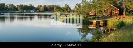 Panorama von Kleinem Haus und Anlegesteg am Wasser mit Zeltplatz im Hintergrund. Oscarshamn. Smaland, Schweden, Skandinavien. Stockfoto