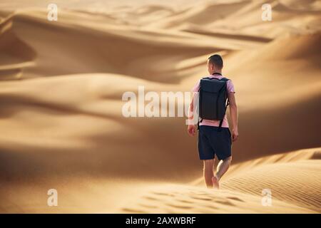 Abenteuer in der Wüste. Junger Mann mit Rucksack, der auf Sanddüne läuft. Abu Dhabi, Vereinigte Arabische Emirate Stockfoto