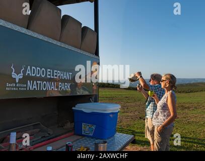 Touristen, die eine Tierwelt suchen und einen Drink auf einer Abendfahrt im Addo Elephant National Park, Eastern Cape, Südafrika, genießen Stockfoto