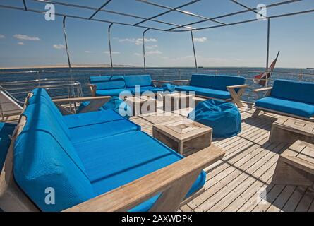 Stern-Teak-Sonnendeck einer großen Luxus-Motoryacht mit Stühlen Couchtisch und tropischem Meerblick Stockfoto