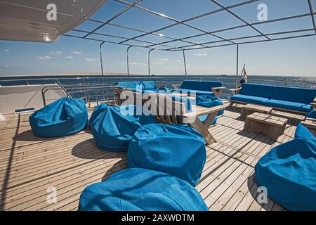 Stern-Teak-Sonnendeck einer großen Luxus-Motoryacht mit Stühlen Couchtisch und tropischem Meerblick Stockfoto