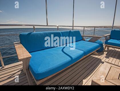 Stern-Teak-Sonnendeck einer großen Luxus-Motoryacht mit Stühlen Couchtisch und tropischem Meerblick Stockfoto