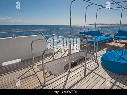 Stern-Teak-Sonnendeck einer großen Luxus-Motoryacht mit Stühlen Couchtisch und tropischem Meerblick Stockfoto