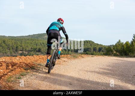 Man Mountainbiking im Wald über eine Schmutzstrecke, Banyeres de mariola Dorf, Costa Blanca, Provinz Alicante, Spanien Stockfoto
