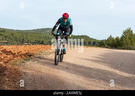 Man Mountainbiking im Wald über eine Schmutzstrecke, Banyeres de mariola Dorf, Costa Blanca, Provinz Alicante, Spanien Stockfoto