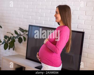 Schöne schwangere Frau verbringt gern Zeit in ihrem Haus. Stockfoto