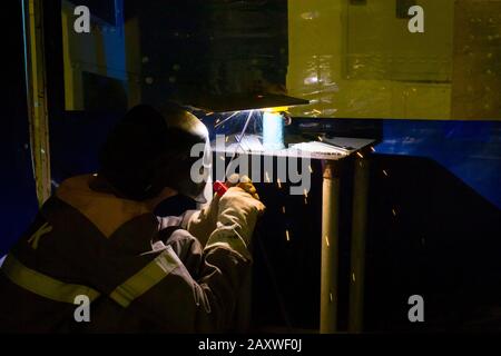 Nahschweißverfahren. Der Arbeitsmann in einer Maske schweißt Metall. Industrietechnologien, Produktionsprozesse. Stockfoto