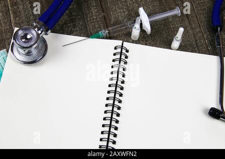 Hintergrund für medizinische Patienten mit Kopierbereich: Ansicht auf offener Randdatei mit weißen leeren Seiten, Stethoskop, Spritze, Fläschchen Stockfoto