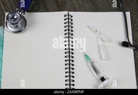 Hintergrund für medizinische Patienten mit Kopierbereich: Ansicht auf offener Randdatei mit weißen leeren Seiten, Stethoskop, Spritze, Fläschchen Stockfoto