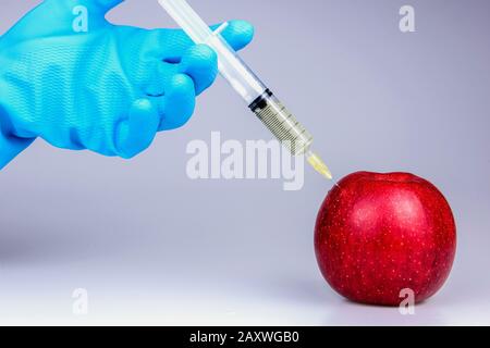 Gentechnisch veränderter roter Apfel mit Spritzen auf weißem Hintergrund.medizinische Spritze injiziert GMO Stockfoto