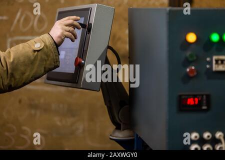 Arbeiter, der das Armaturenbrett von CNC-Maschinen oder die Steuerung an der Maschine im Werk verwendet. Industrie- und Fertigungskonzept Stockfoto