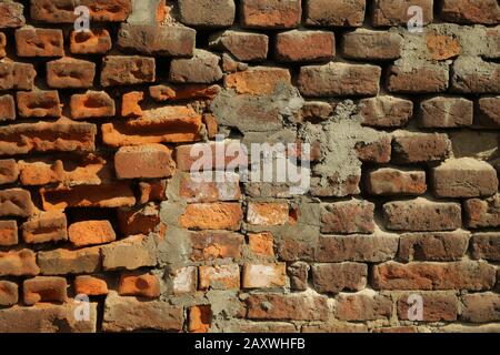 Rot alt abgenutzter Backstein-Wand-Texturhintergrund. Zerbrochene Ziegelwand. Zwei verschiedene Backsteine. Stockfoto