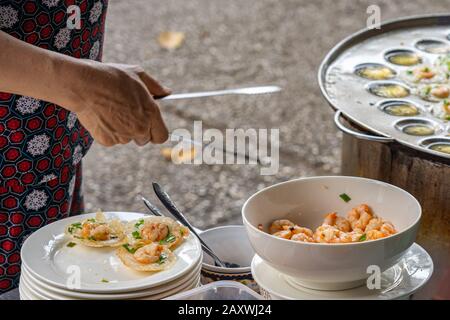 Frau, die vietnamesische kleine Garnelenpfannkuchen auf dem Markt der Händler macht Stockfoto