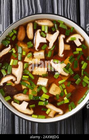 Japanische Miso-Suppe mit Shiitake-Pilzen, Tofu und grünen Zwiebeln in einer Schüssel auf dem Tisch. Vertikale Draufsicht von oben Stockfoto