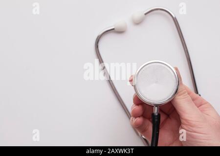 Arzt, der ein medizinisches Stethoskop auf einem einfachen Hintergrund hält Stockfoto