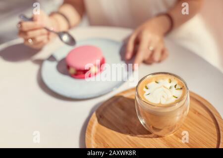 In einem französischen Café essen Sie süße rosafarbene Makronen mit Himbeeren und trinken köstlichen Pistazien Stockfoto